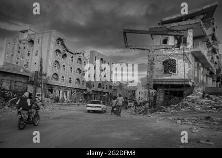 Taiz  Jemen   04 Dez 2015 : Menschen kamen an den Gebäuden vorbei, die während des Krieges zwischen dem Volkswiderstand und der Al-Huthi-Miliz zerstört wurden Stockfoto