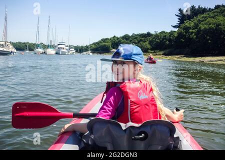 Ein Mädchen sitzt vor einem aufblasbaren Kajak auf einem Fluss im New Forest. Stockfoto