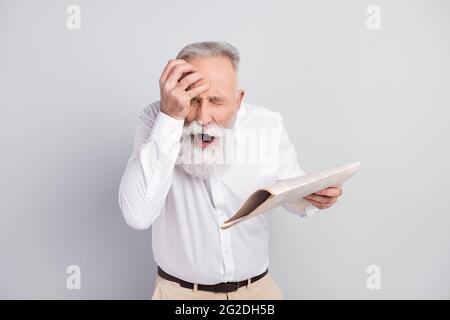 Foto von unglücklich traurig alten Mann halten Hand Kopf leiden Schmerzen halten Zeitung isoliert auf grauem Hintergrund Stockfoto