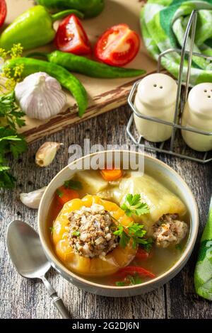 Gesunde Ernährung, Keto-Diät, Mittagessen. Paprika mit Fleisch und Bulgur in einer Brühe mit Gemüse in einer Schüssel auf einem rustikalen Tisch. Stockfoto