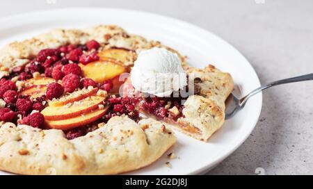 Himbeer- und Pfirsich-Torte, offener Kuchen auf hellem Hintergrund. Stockfoto