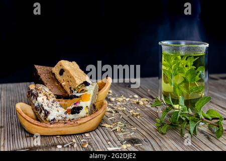 Brownies auf einer Holzschale mit einer frischen Tasse Minztee auf einem Holztisch mit dunklem Hintergrund Stockfoto