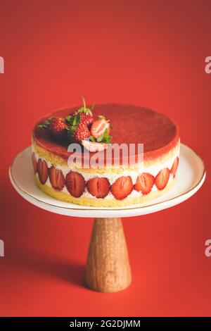 Französischer Erdbeerkuchen Fraisier auf Kuchenständer auf rotem Hintergrund. Stockfoto
