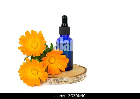 Ringelblumen und Tropfflasche auf Birkenholzscheibe und gelbem Hintergrund. Speicherplatz kopieren. Stockfoto