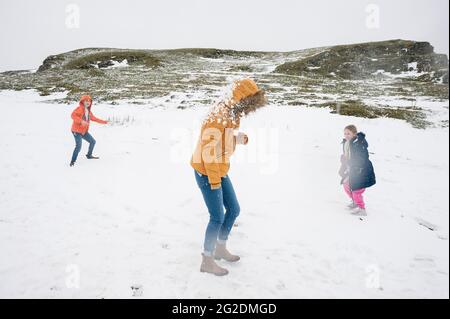 Eine Familie hat Spaß im kalten Schnee, der sich auf dem Boden niedergelassen hat. Stockfoto