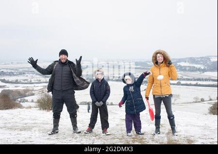 Eine Familie hat Spaß beim Rodeln auf Mill Hill in Shoreham-by-Sea, West Sussex nach einer leichten Schneedecke auf dem Boden. Stockfoto