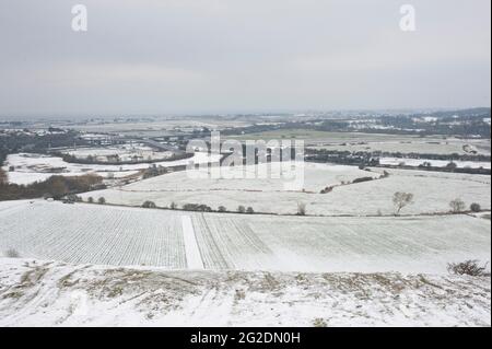 Eine Familie hat Spaß beim Rodeln auf Mill Hill in Shoreham-by-Sea, West Sussex nach einer leichten Schneedecke auf dem Boden. Stockfoto