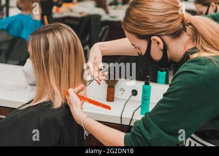 Haarpflege, Frisör schneidet die geschnittenen Enden der Haare und richtet die Länge, die Arbeit der Friseure während der globalen Coronavirus-Pandemie.neu Stockfoto