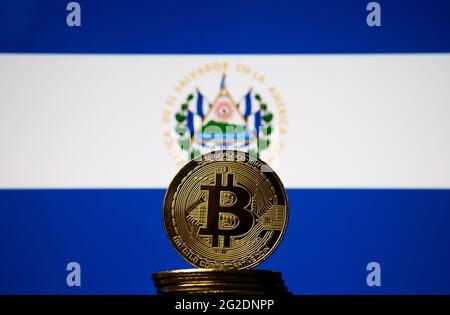 Bitcoin-Münze vor der verschwommenen Nationalflagge von Salvador. El Salvador ist das erste Land, das Bitcoin als gesetzliches Zahlungsmittel annimmt. Co Stockfoto