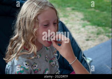 Ein junges Mädchen zeigt stolz ihren Mund und die Lücke in ihren Zähnen, wo ihr erster Zahn herausfiel. Stockfoto