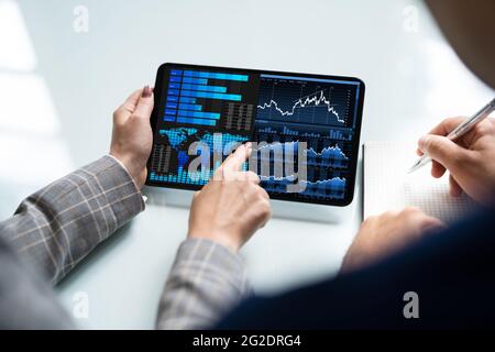 Zwei Analytiker, die KPI-Dashboard auf einem Tablet-Computer verwenden Stockfoto