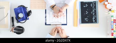 Arzt, der mit dem Patienten am Tisch in der Klinik kommuniziert, Draufsicht Stockfoto