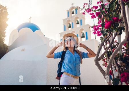 Santorini Tourist mit Rucksack Spaziergänge durch die Kirche mit blauer Kuppel und blühenden Bougainvillea Blumen in Akrotiri. Sommerurlaub Stockfoto