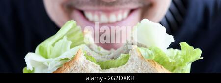 Mann hält Sandwich in den Händen und lächelt Nahaufnahme Stockfoto