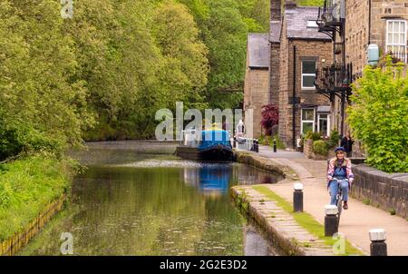 Radfahrerin auf dem Abschleppweg am Hebble End-Kanal, entlang des Rochdale-Kanals, Hebden Bridge, West Yorkshire, Großbritannien Stockfoto