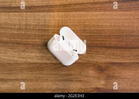 Weißrussland, Minsk Region - 17. März 2020: AirPods Kopfhörer auf Holztisch Textur Hintergrund. Stockfoto