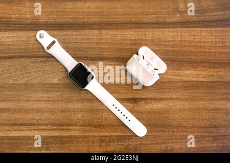 Weißrussland, Minsk Region - 17. März 2020: Apple Watch 4 und AirPods Kopfhörer auf Holzhintergrund. Stockfoto