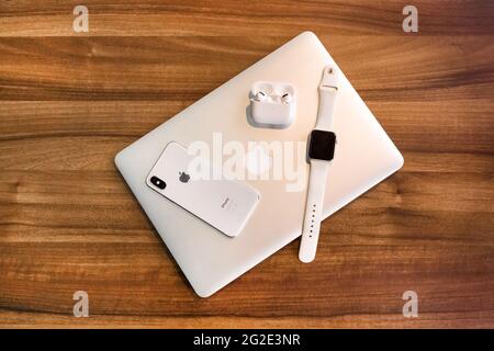 Weißrussland, Minsk Region - 17. März 2020: Set von Apple Gadgets: Laptop, iphone, Apple Watch und airpods auf Holztisch Hintergrund. Stockfoto