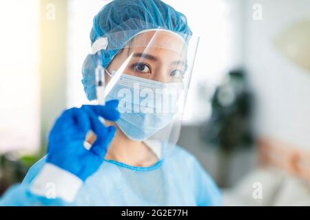 Ärzte oder Krankenschwestern tragen Kittel, Masken, Augenschilde, um eine Injektion mit einer Spritze vorzubereiten Stockfoto