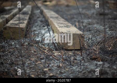 Betonbalken auf dem Boden. Nach einem Brand Materialien bauen. Bleibt auf der verbrannten Erde. Betonblöcke. Stockfoto