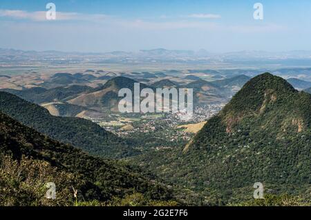 Fernsicht vom Aussichtspunkt Soberbo auf die Gemeinde Guapimirim zwischen der bergigen Region Serra do Mar (Sea Ridge) unter wolkenblauem Himmel. Stockfoto