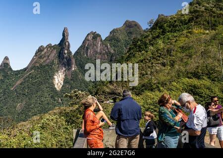 Touristen in Soberbo Aussichtspunkt betrachten den Blick auf die Our Lady Finger, God's Finger und Cabeca de Peixe (Fish Head) Gipfel an einem klaren sonnigen Tag. Stockfoto