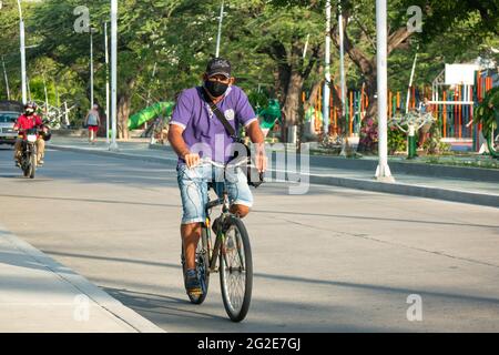 Santa Marta, Magdalena, Kolumbien - 22 2021. Mai: Lateinischer Mann mit schwarzer Maske und Mütze radeln morgens im Avenue Park Stockfoto