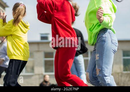 Kinder tanzen auf der Straße. Viele Kinder tanzen zur Musik in der Stadt. Schüler treten bei einer Tanzstunde auf. Stockfoto