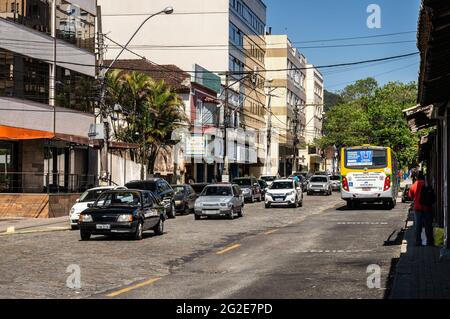 Alfredo Rebelo Filho Straße Südseite Blick mit Verkehr durch einen Bus und einige lokale kleine Unternehmen und Wohnungen unter klarem sonnigen blauen Himmel. Stockfoto