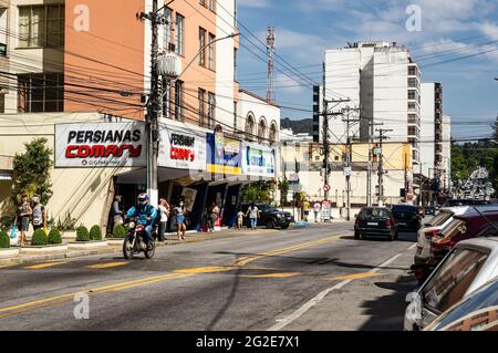 Südansicht der sehr langen Oliveira Botelho Avenue mit Verkehr durch Autos geparkt, in der Nähe Jorge Lossio Straße unter sonnigen klaren blauen Himmel Tag. Stockfoto