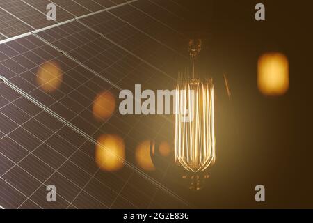 Vintage antike elektrische Lampe vor dunklem Hintergrund und Solarkollektor Platten - Konzept der Ideen Stockfoto