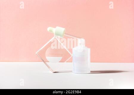 Gesichtsserumflasche mit Pipette und gläserner Säule. Verpackung von Beauty-Produkten mit Tropf und natürlichen Inhaltsstoffen. Peachy Hintergrund für Text Stockfoto