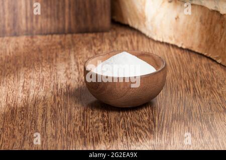 Backpulver (Natriumbicarbonat) in einer Holzschale; Foto auf Holzhintergrund. Stockfoto