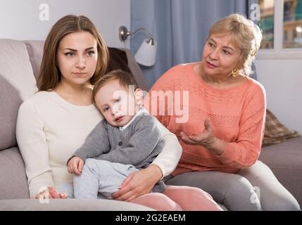 Erwachsene Frauen mit ihrer Mutter haben Meinungsverschiedenheiten über die Elternschaft des Kindes Stockfoto