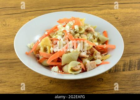 Pasta-Gericht mit kaltem Lachs mit Karotten und Feta-Käse und griechischem Feta-Käse-Salatdressing auf weißer Schüssel Stockfoto