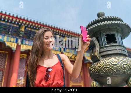 Mädchen, das mit dem Smartphone an der alten Bronzeskulptur in Peking ein Selfie bei der touristenattraktion in china macht. Asien Tourismus Reisen. Menschen Stockfoto