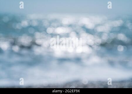 Abstrakte Natur Sommer oder Frühling Meer Meer Hintergrund. Kleine Wellen auf der goldenen, warmen Wasseroberfläche verwischen sich in Bewegung mit Bokeh-Lichtern vom Sonnenuntergang. Urlaub Stockfoto