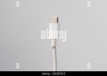 Abgerissenes Kabel zum Aufladen eines Mobiltelefons vom Typ si auf weißem Hintergrund. Speicherplatz kopieren. Stockfoto