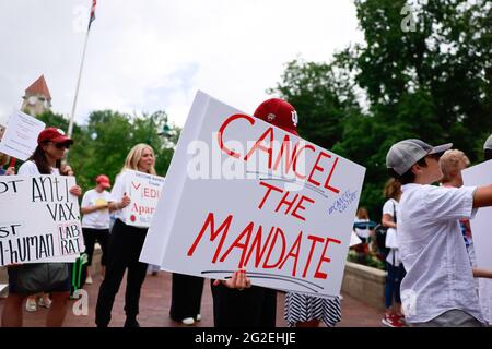 Bloomington, USA. Juni 2021. Demonstranten, die Plakate halten, versammeln sich während der Demonstration an den Sample Gates der Indiana University.Anti-Vaxxe und Anti-Masker versammelten sich an den Sample Gates der Indiana University, um gegen die obligatorischen Covid-Impfungen zu protestieren, die die IU für Studenten, Mitarbeiter und Lehrkräfte im kommenden Herbstsemester verlangt. Die Demonstranten sagen, dass ihre Verfassungsrechte verletzt werden und haben eine Klage eingeleitet. Kredit: SOPA Images Limited/Alamy Live Nachrichten Stockfoto