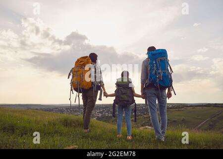 Familie mit Rucksäcken. Touristen stehen in der Natur Wandern am Abend in der Nacht. Rückansicht. Stockfoto