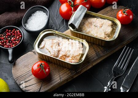 Dosen Wild Alaska Lachs Set, auf Holzschneidebrett, auf schwarzem Hintergrund mit Kräutern und Zutaten Stockfoto