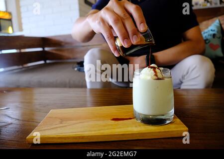 Mann gießt Espresso in EIN Glas Avocado-Eis Stockfoto