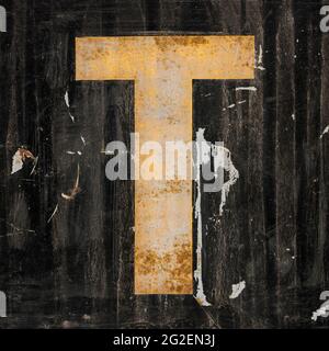 Verwitterter goldener Buchstabe T auf schwarzem Hintergrund Stockfoto