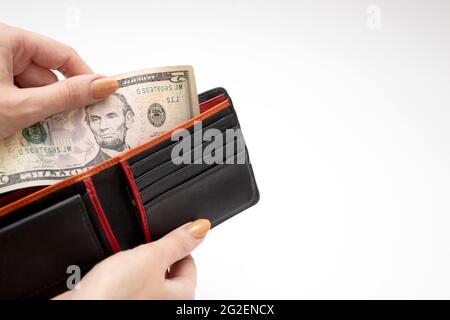 Papiergeld in Brieftasche mit Frauenhand. Frau nimmt Dollargeld aus der Brieftasche Stockfoto