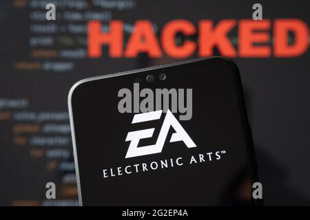 EA Electronic Arts-Logo auf einer Silhouette des Smartphones und einfacher Quellcode auf mit Wort GEHACKT auf verschwommenem Hintergrund. Konzept. ECHTES FOTO, Stockfoto