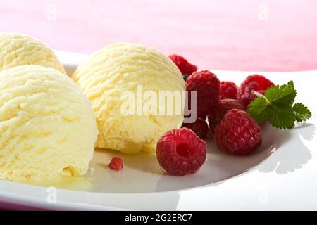 Drei Kugeln Vanilleeis garniert mit Himbeeren Stockfoto
