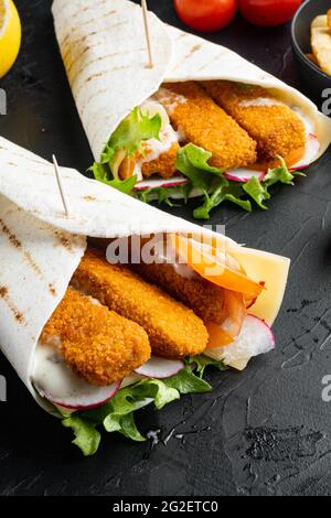 Tortilla-Rolle mit Fischfinger, Käse- und Gemüseset, auf schwarzem Hintergrund Stockfoto