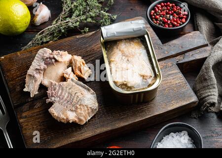 Set aus Wildlachs in Dosen, auf Holzschneidebrett, auf altem dunklen Holztisch mit Kräutern und Zutaten Stockfoto
