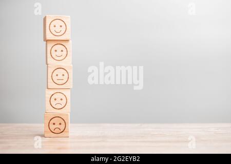 Emotionsgesicht-Symbol auf Holzblöcken. Service Rating, Ranking, Customer Review, Zufriedenheit, Bewertung und Feedback-Konzept Stockfoto