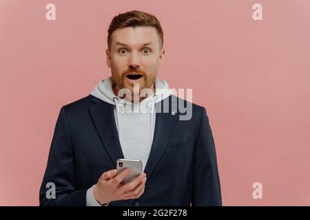 Beeindruckter Mann beim Lesen der neuesten Nachrichten mit überraschendem Gesichtsausdruck Stockfoto